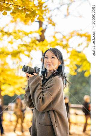A woman taking a picture of autumn leaves 106506593