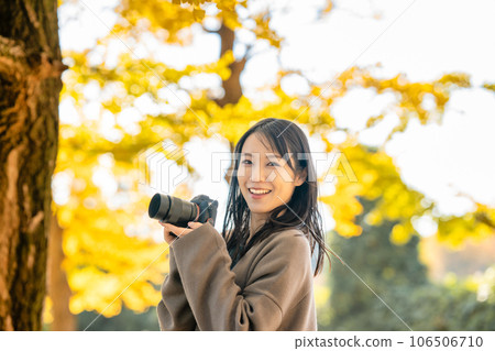A woman taking a picture of autumn leaves 106506710