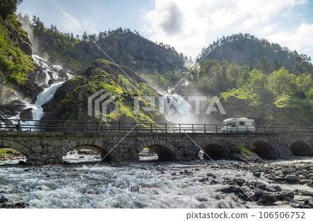 Holiday trip in motorhome, Caravan car Vacation. RV traveling on the road Latefossen Waterfall Odda Norway. Latefoss is a powerful, twin waterfall. 106506752