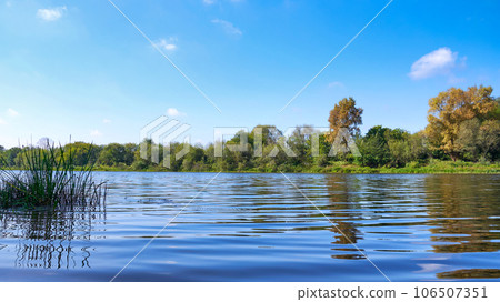 Landscape with a river and trees against a blue sky on a sunny day 106507351