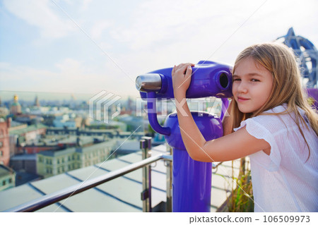 a teenage girl looks into the Binoscope from the observation deck at a height. a teenage girl looks into the Binoscope from the observation deck at a height. 106509973