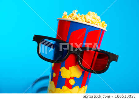 Movie clapper, pop corn, 3D glasses and film reel on blue background. Collage design 106510055