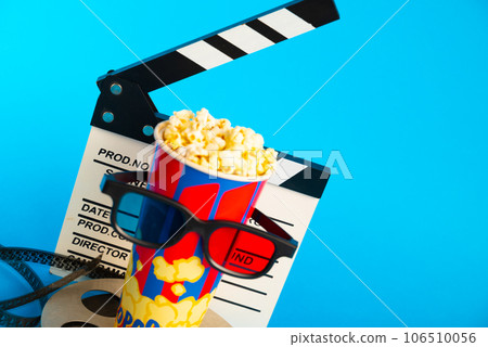 Movie clapper, pop corn, 3D glasses and film reel on blue background. Collage design Movie clapper, pop corn, 3D glasses and film reel on blue background. Collage design 106510056