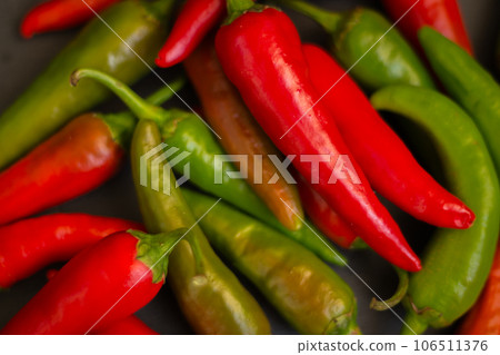 Red hot chilli peppers. Heap of red and green pepper. Bright natural background. Cayenne peppers. Colourful spicy peppers. Organic vegetables. Spicy mexican food.  106511376