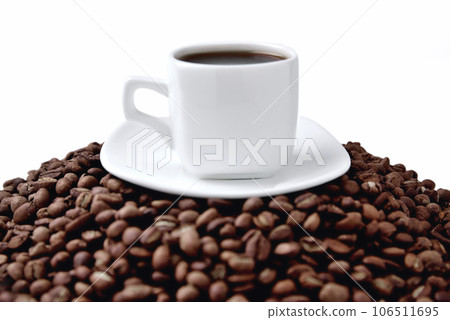 white cup of coffee on a white saucer stands on a hill of coffee beans on a white background white cup of coffee on a white saucer stands on a hill of coffee beans on a white background 106511695