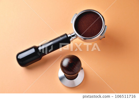 coffee horn with natural ground coffee and temper on an orange background 106511716