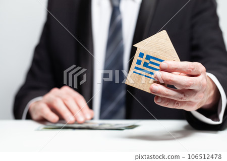 Businessman hand holding wooden home model with Greek flag. insurance and property concepts 106512478