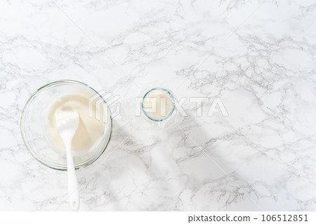 Flat lay. Transferring homemade royal icing into the piping bags for decorating sugar cookies. 106512851