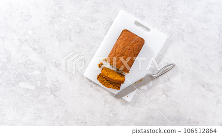 Flat lay. Sliced homemade pumpkin bread on a white cutting board. Flat lay. Sliced homemade pumpkin bread on a white cutting board. 106512864