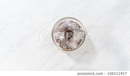 Flat lay. Gingerbread bundt cake with caramel filling, buttercream frosting, and powdered sugar dusting on the kitchen counter. Flat lay. Gingerbread bundt cake with caramel filling, buttercream frosting, and powdered sugar dusting on the kitchen counter. 106512957