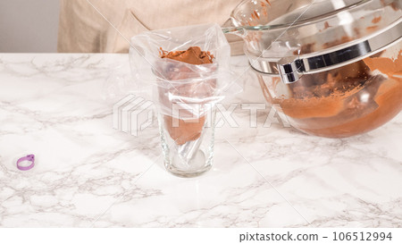 Step by step. Chocolate ganache frosting in a piping bag with a metal tip. 106512994