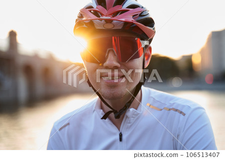 Man is wearing protective helmet, sunglasses and sportswear during evening ride in city. Man is wearing protective helmet, sunglasses and sportswear during evening ride in city. 106513407