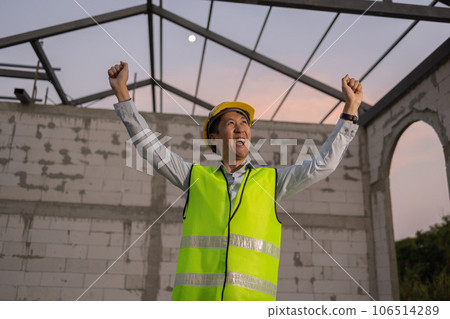 Asian engineer in uniform and helmet at construction site being happy and smiling for success. Successful project and happiness expression after work concept Asian engineer in uniform and helmet at construction site being happy and smiling for success. Successful project and happiness expression after work concept 106514289