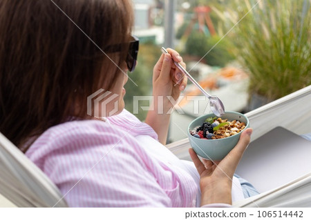 young woman eating chia pudding with nuts and berries young woman eating chia pudding with nuts and berries 106514442