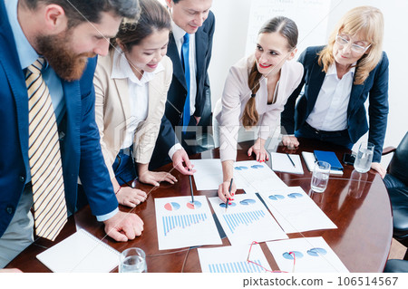Multi-ethnic team of five dedicated specialists smiling while analyzing various charts with positive statistics Multi-ethnic team of five dedicated specialists smiling while analyzing various charts with positive statistics 106514567
