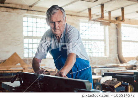 Experienced master carpenter working with wood milling machine 106514572