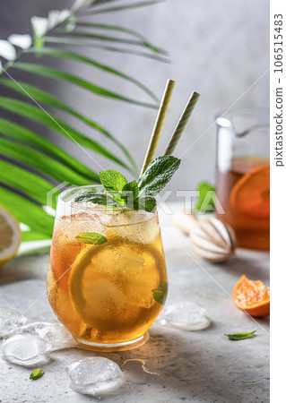 Cold summer orange lemonade with mint and ice cubes in a glass tropic style Cold summer orange lemonade with mint and ice cubes in a glass tropic style 106515483