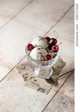 Ice cream in balls with cherry and chocolate in glass bowl on beige tile background, summer refreshing morning dessert, vertical 106515484