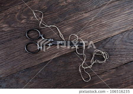 Antique old vintage retro scissors with thread on wooden table. Antique old vintage retro scissors with thread on wooden table. 106516235