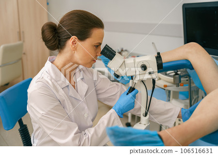 Female gynecologist examining patient on chair with gynecological equipment in woman consultation 106516631