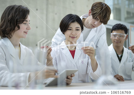 Laboratory image of young men and women in white coats conducting experiments Laboratory image of young men and women in white coats conducting experiments 106516769
