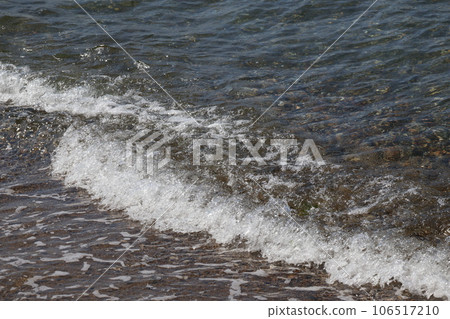 Seascape of the shore with white foamy waves crashing against the shore Seascape of the shore with white foamy waves crashing against the shore 106517210