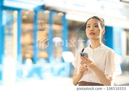 Young woman looking at smartphone in the city at dusk 106518333