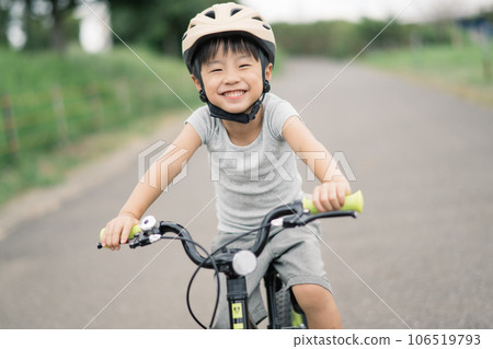 A boy wearing a helmet and riding a bicycle A boy wearing a helmet and riding a bicycle 106519793