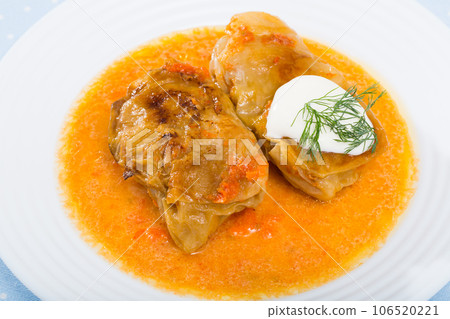 Homemade cabbage rolls in leaves of cabbage at plate with sour cream Homemade cabbage rolls in leaves of cabbage at plate with sour cream 106520221