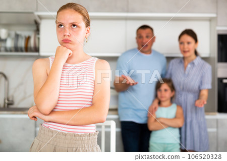 Offended teen girl listening to reprimand of displeased parents Offended teen girl listening to reprimand of displeased parents 106520328