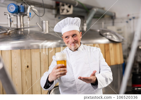 Portrait of positive man brewmaster with glass of beer 106520336