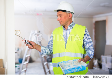 Man builder painting wall in apartment 106520475
