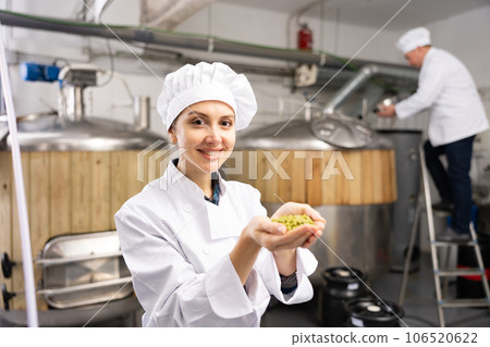 Smiling woman brewer holding bunch of hop pellets Smiling woman brewer holding bunch of hop pellets 106520622