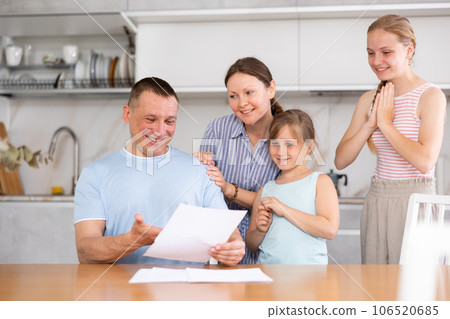 Cheerful man with wife and teenage daughters reading letter Cheerful man with wife and teenage daughters reading letter 106520685