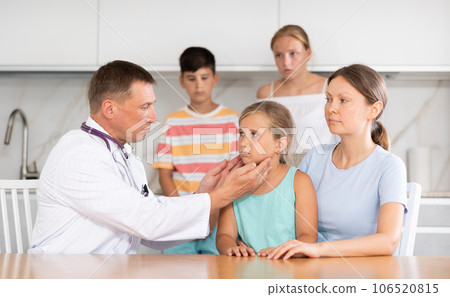 Man doctor examines throat and lymph nodes of small girl patient at home Man doctor examines throat and lymph nodes of small girl patient at home 106520815