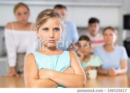 Little girl is upset after fight with her sisters and brothers. Turned away from whole family. Looking at camera 106520817
