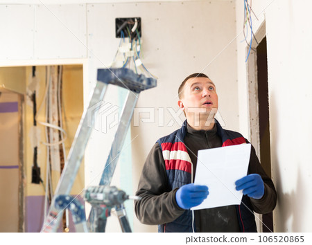 Repair man planning his work in apartment and checking documentation 106520865
