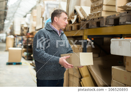 Male seller holding box in warehouse 106520893