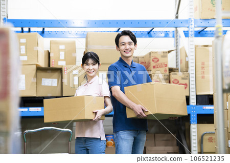 Male and female employees working in a warehouse 106521235