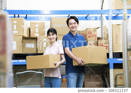 Male and female employees working in a warehouse 106521237