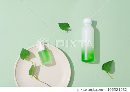 Minimal scene of empty label beauty containers decorated with fish mint leaves. Research and development beauty skincare concept Minimal scene of empty label beauty containers decorated with fish mint leaves. Research and development beauty skincare concept 106521982