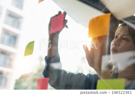 Business woman brainstorming with creative idea working for strategy and planning. Female writing ideas on sticky note for reminder or startup new project Business woman brainstorming with creative idea working for strategy and planning. Female writing ideas on sticky note for reminder or startup new project 106522361