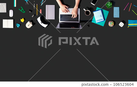 Person using a laptop computer with office supplies 106523604