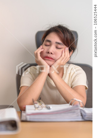 Stressed Asian woman having Tired and Sleepy while working, female businesswoman having headache at office, Exhausted woman with documents folder stack at home late night. Overworked and Overtime Stressed Asian woman having Tired and Sleepy while working, female businesswoman having headache at office, Exhausted woman with documents folder stack at home late night. Overworked and Overtime 106525444