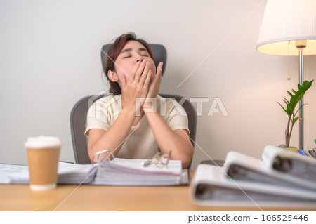 Stressed Asian woman having Tired and Sleepy while working, female businesswoman having headache at office, Exhausted woman with documents folder stack at home late night. Overworked and Overtime Stressed Asian woman having Tired and Sleepy while working, female businesswoman having headache at office, Exhausted woman with documents folder stack at home late night. Overworked and Overtime 106525446