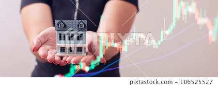 The concept of buying and selling real estate. A man with a model of a house on the background of the forex chart. 106525527