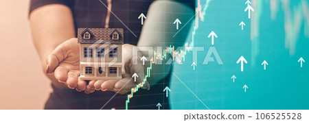 The concept of buying and selling real estate. A man with a model of a house on the background of the forex chart. The concept of buying and selling real estate. A man with a model of a house on the background of the forex chart. 106525528