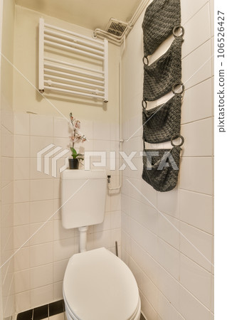 a white toilet in a bathroom with towel hanging on the wall next to the toilet bowl and radiaing rack a white toilet in a bathroom with towel hanging on the wall next to the toilet bowl and radiaing rack 106526427