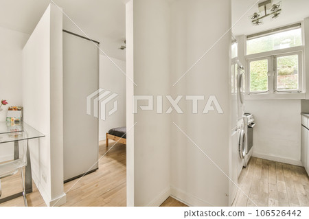 a bathroom with white walls and wood flooring the room is well lit by natural light from the large window 106526442