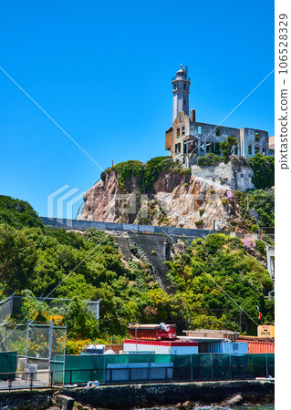 Bright blue sky overhead Alcatraz Island lighthouse with pier view of island 106528329